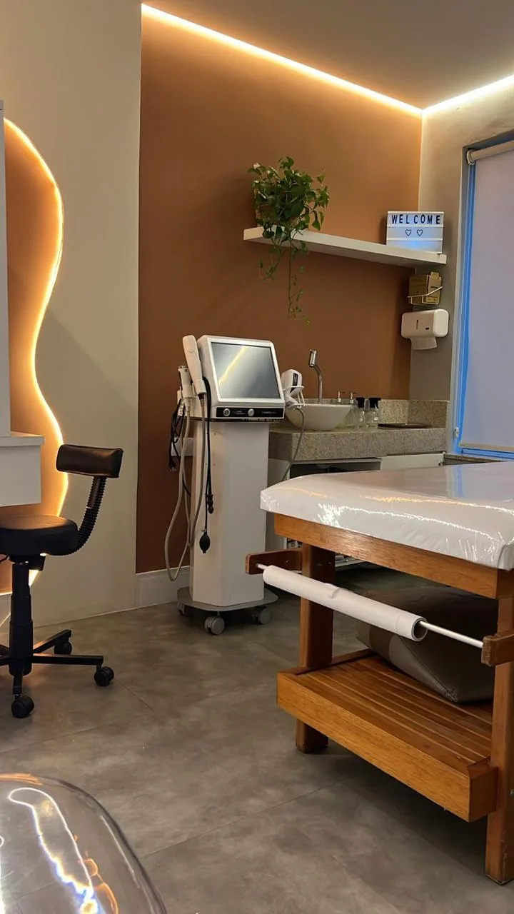 Sala de procedimentos da Clínica Coronato — paleta terracota, iluminação cove e aparelhos de estética