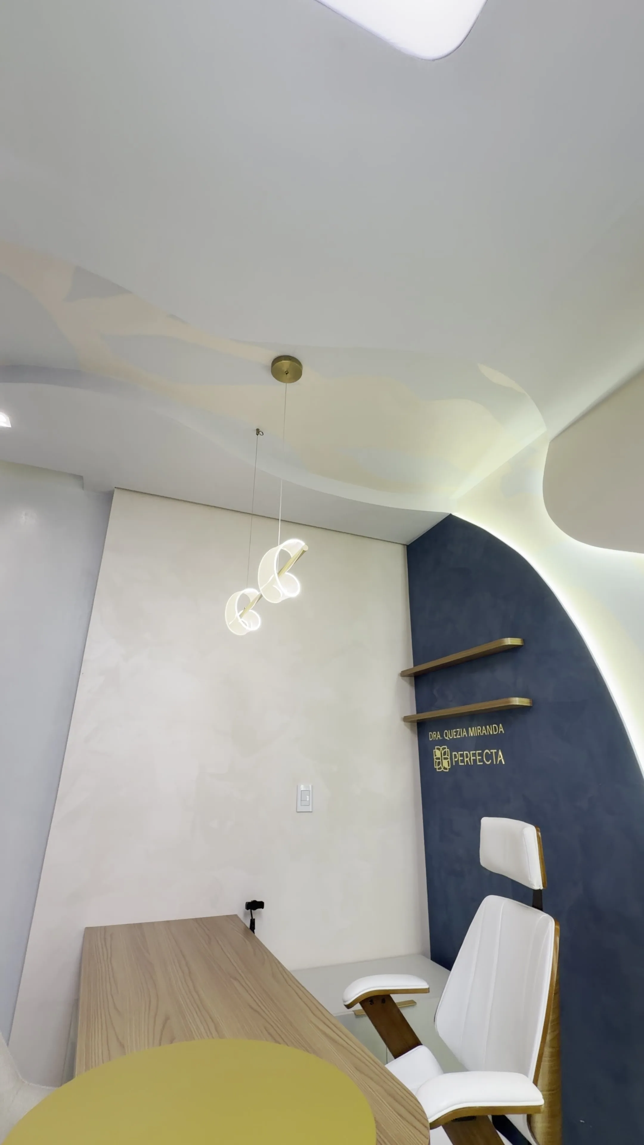 Consultório odontológico da Clínica Perfecta — parede azul marinho e teto escultural