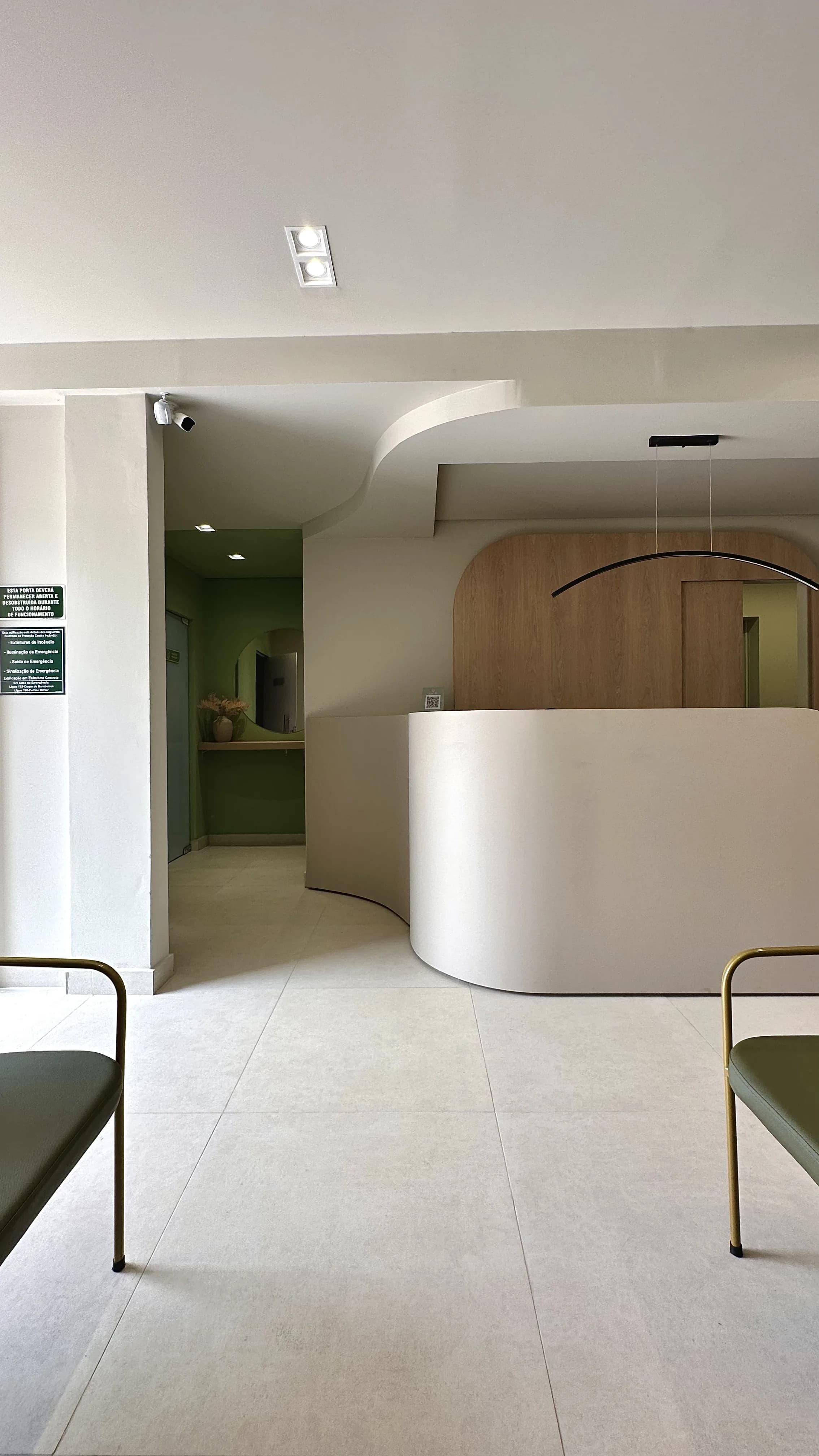 Recepção da Clínica Unilab — balcão curvo branco e parede verde escura